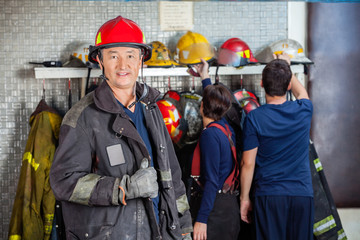 Fototapeta premium Smiling Fireman Standing At Fire Station