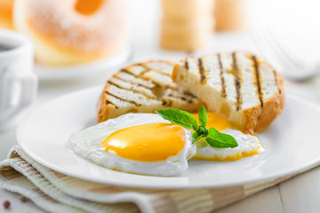 Fried eggs with toasts, coffee and donuts, traditional breakfast, close-up