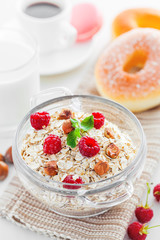 Oatmeal with raspberry and hazelnut. Breakfast with coffee on table.