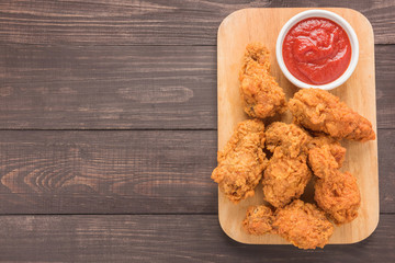 fried chicken drumstick and ketchup on wooden background
