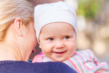 Cute baby girl looking out from mother's back