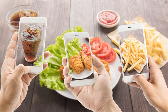 riends using smartphones to take photos of fried chicken and fre