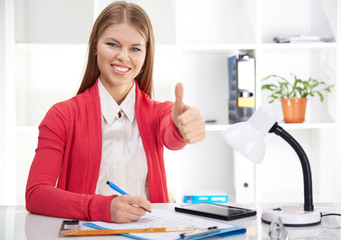 Happy business woman showing thumb up working on blueprint in the office. Concept of success and...