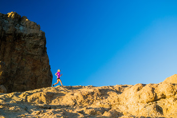 Woman trail running on rocky mountains