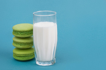 green macaroon on a blue background with milk in a glass beaker