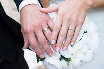 Obraz na płótnie Canvas close-up shot of young married couple hands with wedding ring on bride bouquet