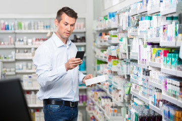 Customer Checking Information On Mobile Phone In Pharmacy