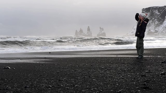 Beautiful traveler girl walking on the black beach of Vik Myrdal in Iceland, enjoying wonderful winter landscape of North Atlantic Ocean. Full HD Video 1920x1080
