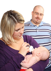 Young overweight parents feeding little baby. Picture with shallow DOF.