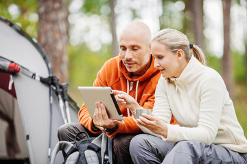 Couple of backpackers looking on tablet computer