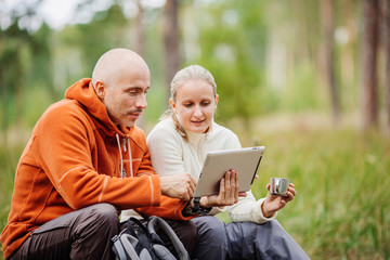 Couple of backpackers looking on tablet computer