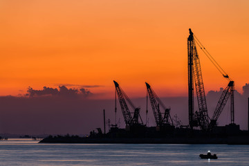 Fototapeta premium Chioggia, le gru del Mose al tramonto con un pescatore in barca