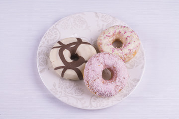 Three strawberry and chocolate donuts on a plate