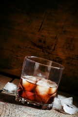 Cold whiskey with ice in a dark cellar, selective focus