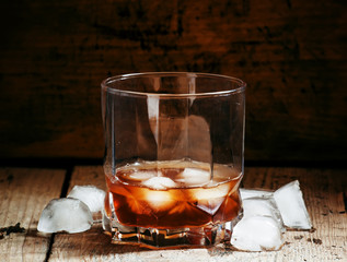 Cold whiskey with ice in a dark cellar, selective focus