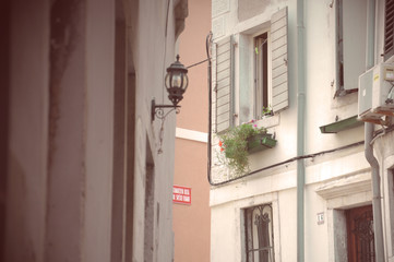 Fototapeta na wymiar Street of the old Piran: Window with flowers and lantern