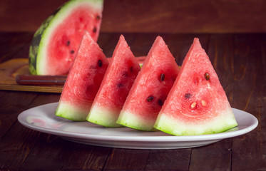 slices of watermelon in a white plate on a wooden background