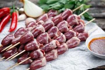 Ready to cook Duck Heart stringed on skewers BBQ , chili pepper. decorated with greens and vegetables. background.