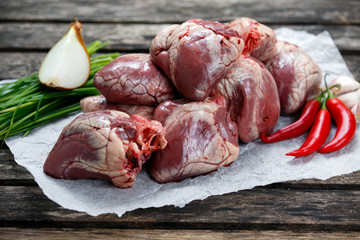 Raw Lamb Hearts on crumpled paper, decorated with vegetables. on old wooden table.