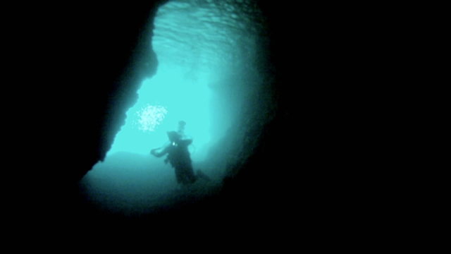 Scuba divers swimming through dark underwater cave Mexico HD 0046