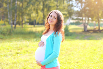 Pretty smiling pregnant woman in sunny summer day