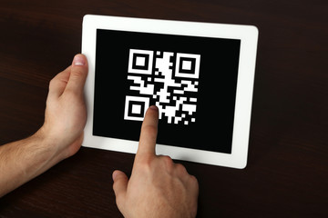 Hands holding tablet PC with QR code on screen