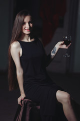 Fototapeta na wymiar Young woman with glass of red wine in the room