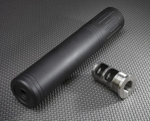 Silencer and the adapter to easily mount it on a gun seen on a rubber work mat.