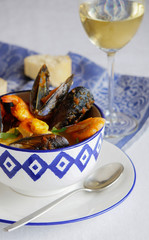 french soup Bouillabaisse with mussels, clams, langoustines, squid, cod, trout in white bowl with...