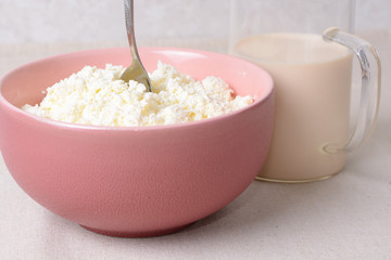 Air cottage cheese with spoon in a deep plate and glass of milk