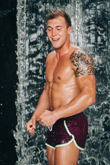 muscled shirtless young man enjoy waterfall