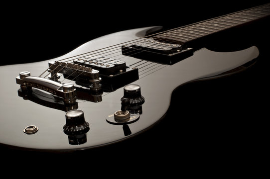glossy black electric guitar isolated on black background