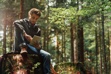 Young man using a digital tablet in the woods