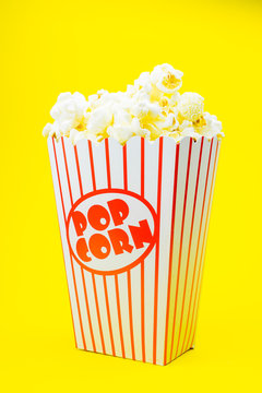 Classic box cinema popcorn on yellow background..