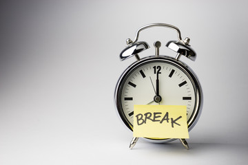 Alarm clock with sticky paper note on white background..