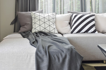 Light gray L shape sofa with varies pattern and white pillows in