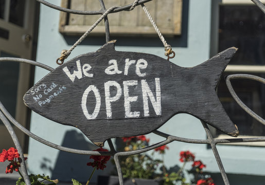 Wooden 'We Are Open' sign hanging outside a shop in St Ives, Cornwall, UK