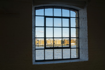 Across River Thames through old wahrehose window, Wapping, London buildings