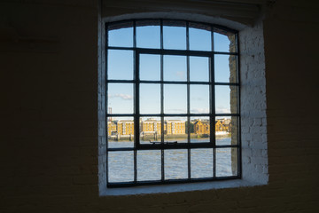 Fototapeta premium Across River Thames through old wahrehose window, Wapping, London buildings