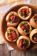 Yorkshire puddings with sausage and green peas closeup vertical top view
