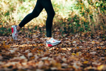 woman runs for fall foliage, shoes closeup, motion blur
