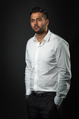 Junger Mann im weißen Hemd mit den Händen in den Taschen