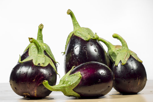 Purple eggplants on wooden table and white background