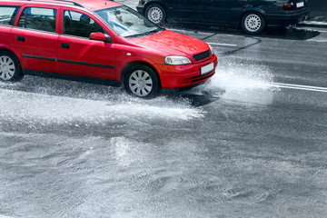 Obraz na płótnie Canvas splashing red car on flooded street