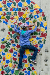 Young girl climbing a fun, colourful, climbing wall
