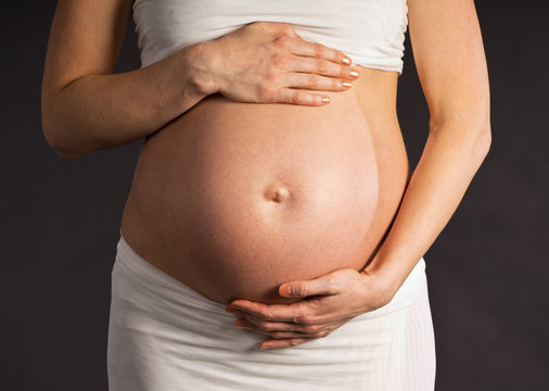 Pregnant woman's belly and hands around the abdomen