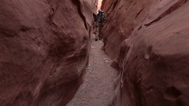 Photographer walking through slot canyon Southwest desert Utah HD. Beautiful mountains and valley with steep sandstone crevasse. Nature recreation and photography. 1568