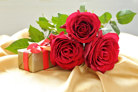 Roses  with gift box on gold tablecloth.