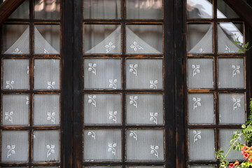 Wooden closed window with white lace curtains,