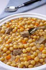 Pot of chickpeas with meat on a white background